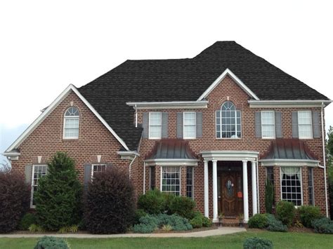 red brick house with charcoal metal roof|black shingles on brick house.